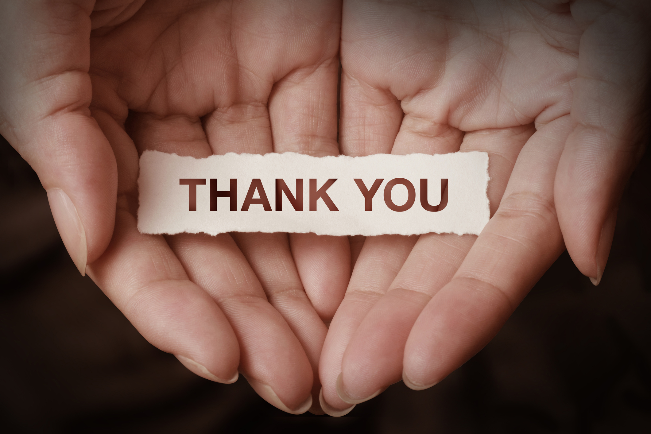 Two hands holding a small thank you note